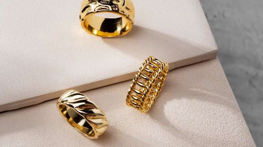 سه حلقه طلایی درخشان روی سطوح کرم و سفید