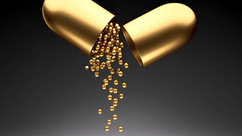 کپسول طلایی که باز است و از دورن آن گوی‌های طلایی کوچک به بیرون می‌ریزد.
