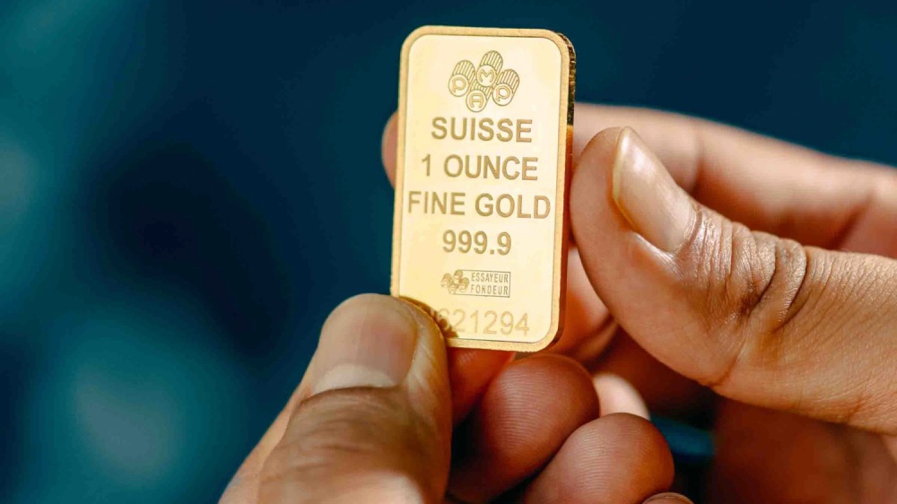 یک انس شمش طلای خالص suisse در دست یک نفر