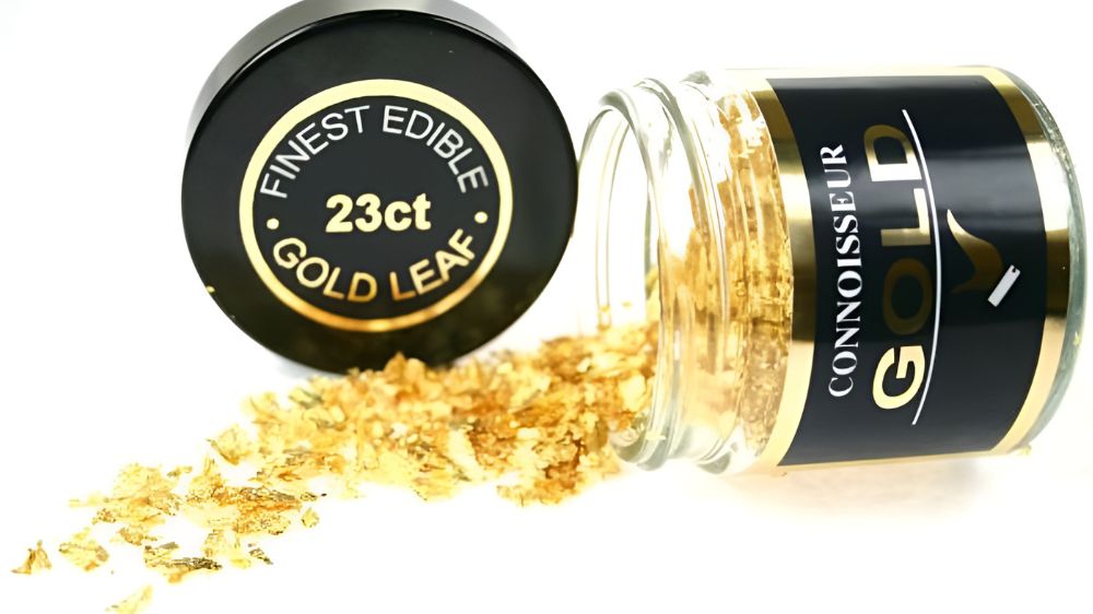 یک شیشه باز که ورق طلای خوراکی از درون آن به بیرون ریخته است.