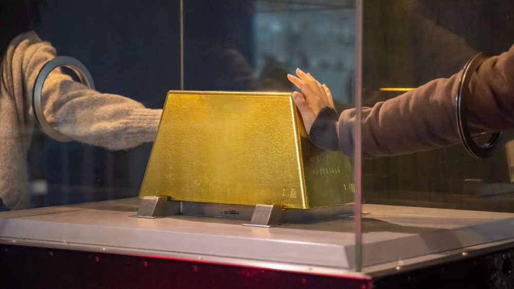 دو نفر در حال لمس بزرگترین شمش طلا