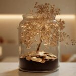 یک گلدان شیشه‌ای با چند سکه در کف آن که یک درخت طلایی از آن بیرون آمده