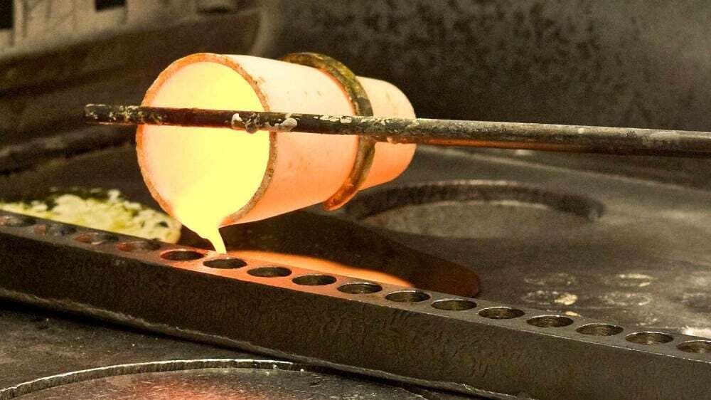طلای مذاب از بوته‌ی گداخته در حال ریخته شدن به داخل قالب‌های شمش