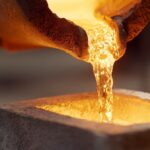 نمای نزدیک از ریختن فلز مذاب درخشان از یک بوته آهنگری به داخل قالب سنگی